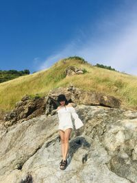 Rear view of woman standing on rock against sky