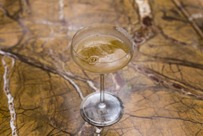 Amber cocktail in martini glass with sugar on rim set on beautiful veined marble table