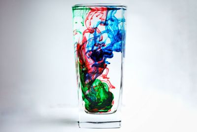 Close-up of multi colored glass over white background