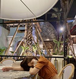 Young woman wearing mask lying on table at cafe