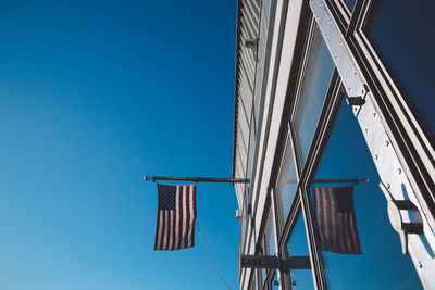 Low angle view of empire state building with american flags against clear sky