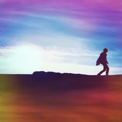 Silhouette of woman standing against cloudy sky