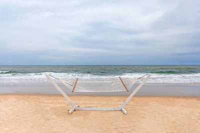 Deck chairs on beach against sky