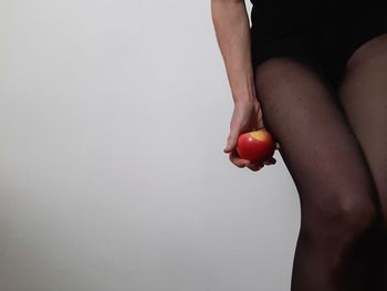Low section of woman with apple against white background