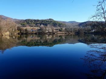 Scenic view of lake and mountains against clear blue sky