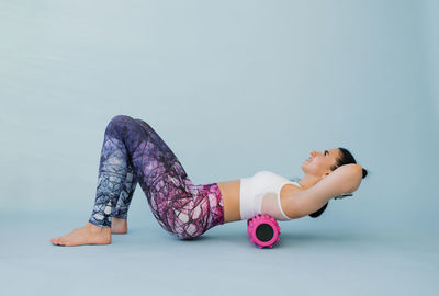 Woman performs myofascial relaxation of the hyperflexible muscles of the back with a massage roller