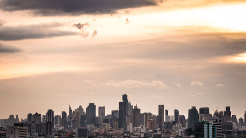 Modern buildings in city against sky during sunset