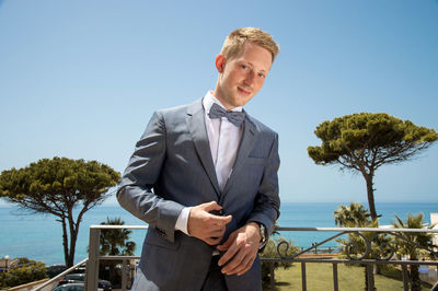 Portrait of smiling businessman standing against sky