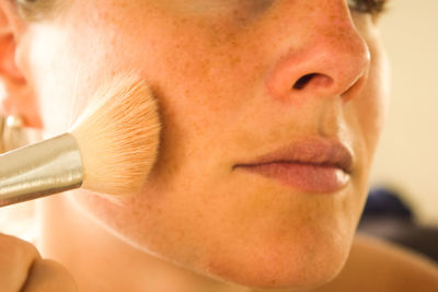 Close-up of woman applying make-up with brush