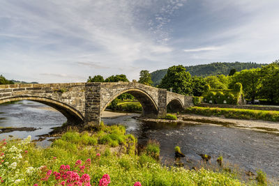 Arch bridge over river against sky