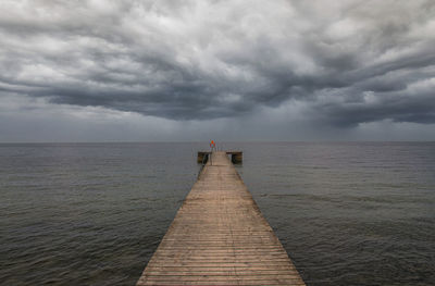 Pier over sea against cloudy sky