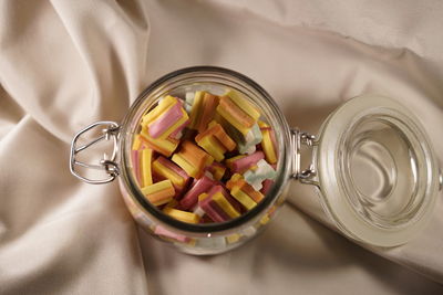 High angle view of candies in jar on tablecloth