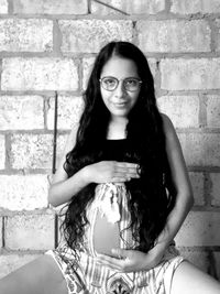 Portrait of smiling young woman against wall