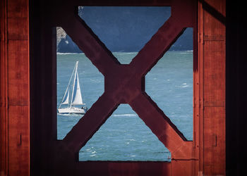 Directly below shot of sea and sailboat seen through golden gate bridge