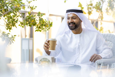 Smiling man wearing traditional clothing sitting at outdoor cafe