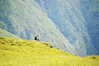 Distant view of people sitting against mountains