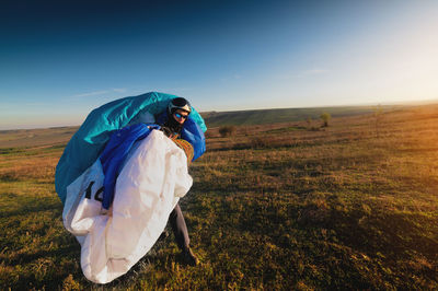 Male paraglider with a parachute in his hands on a sunny day on the field. preparing for a flight or