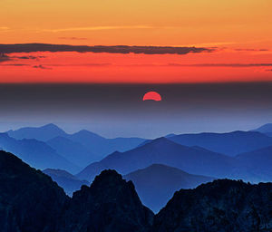 Scenic view of silhouette mountains against romantic sky at sunset