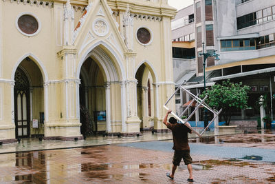 Full length rear view of man standing in building during rainy season