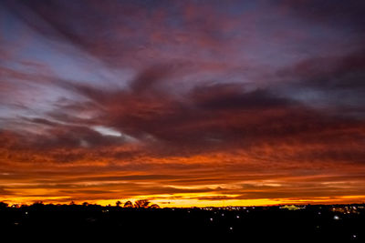 Silhouette landscape against dramatic sky during sunset