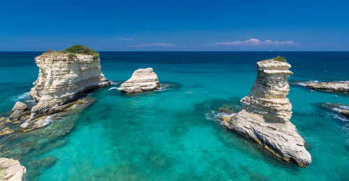 Panoramic shot of rocks in sea against blue sky