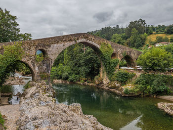 Arch bridge over river against sky