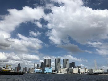 Sea by modern buildings against sky in city