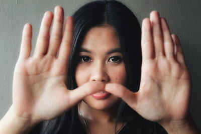 Portrait of beautiful young woman showing stop gesture against wall