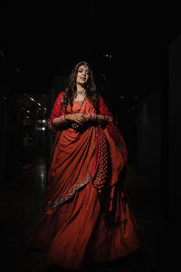 Portrait of woman with arms raised standing at night