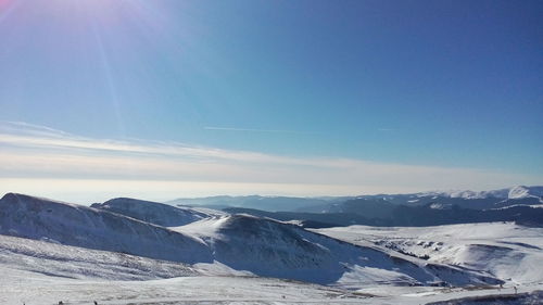 Scenic view of snowcapped mountains against blue sky