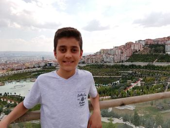 Portrait of boy standing on cityscape against sky