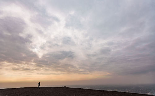 Silhouette man standing on beach against sky during sunset