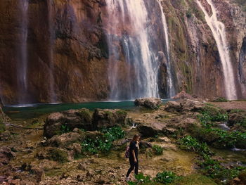 Side view of woman walking against waterfall