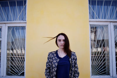 Portrait of young woman against yellow wall