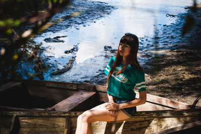 Portrait of smiling young woman sitting by lake