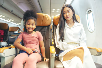 A happy little child and woman are seated in a passenger airliner.