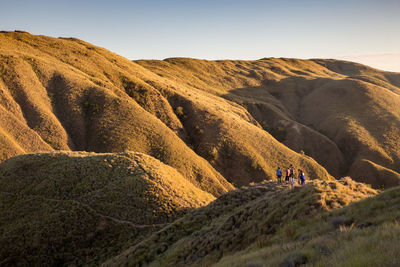 People on mountain against sky on sunny day