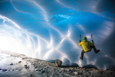Man ice climbing on glacial ice in ice cave.