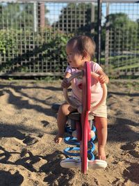 Cute girl sitting on play equipment at playground