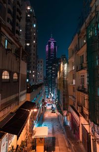 Illuminated street amidst buildings in city at night