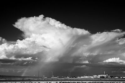 Panoramic view of factory against storm clouds