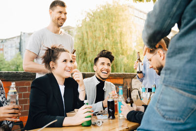 Male and female friends laughing while sitting at social gathering