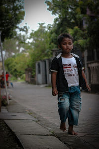 Portrait of teenage boy standing on footpath