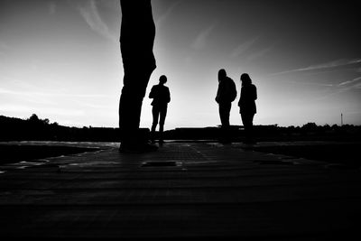 Silhouette people on pier against sky