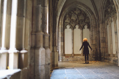 Rear view full length of woman standing in historic church corridor