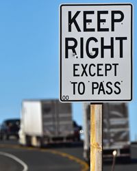 Close-up of information sign on road against sky