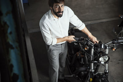 Portrait of businessman looking at motorcycle parked in garage