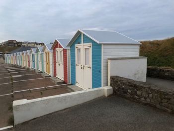 Beach huts by buildings against sky