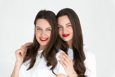 Two beautiful women twin sisters posing white background