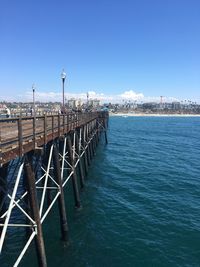Pier over sea against clear blue sky